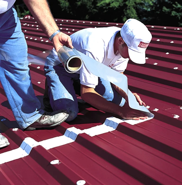 Reinforcing fabric being embedded over the seams on a metal roof