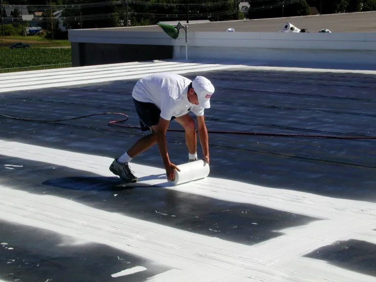 Roofer rolling reflective coating onto a flat commercial roof